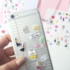 a person holding an iphone case with stickers on the front and back of it