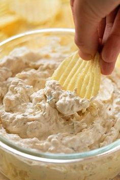 a person dipping chips into a bowl of dip