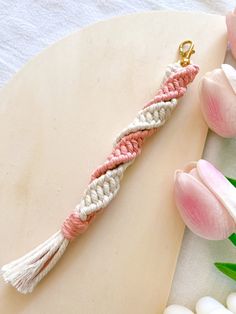 a pink and white crocheted keychain next to some tulips