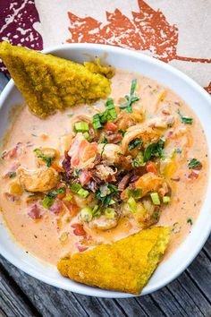 a white bowl filled with soup and tortilla chips on top of a wooden table