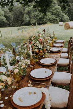 a long wooden table with plates and flowers on it