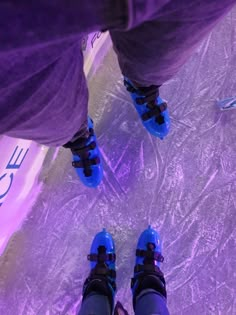 the legs and feet of a person wearing blue shoes standing on an ice skating rink