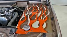 the engine compartment of a car with flames painted on it's hood and an orange flame design