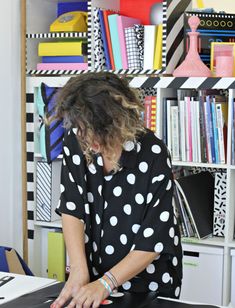 a woman is typing on her laptop in front of a bookcase