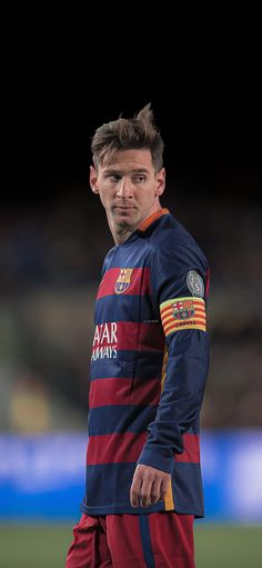 a man standing on top of a soccer field wearing a blue and red striped shirt