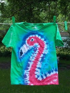 a tie - dyed t - shirt hanging on a clothes line with trees in the background