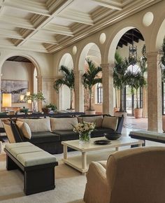 a living room filled with lots of furniture next to tall pillars and arches on the ceiling