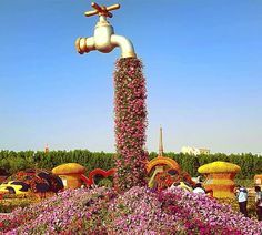 there are many flowers growing on the top of this water faucet in the park