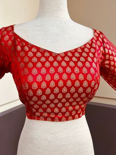 Pure Banarasi Red Color Blouse with small Gold Buttis in Zari Weaving. Comes with Cups attached to the blouse.  Please note : Blouses has margin to open 2 sizes up.  Item : Ready to Wear Blouse Color : Red  Blouse Fabric : Pure Banarasi Silk Blouse Fitting : Princess Cut  Lining : Yes, it is fully lined  Padded or Non-Padded : Padded  Closure: Back Closure with hooks. Ready-to-Wear : Yes Disclaimer - : -This is a Standard Size blouse. We do not guarantee perfect fit as every body and shape is di Red Unstitched Brocade Blouse Piece, Zari Weaving Top For Wedding, Red Unstitched V-neck Blouse Piece, Red Banarasi Silk Blouse For Transitional Season, Elegant Tops With Zari Weaving For Festivals, Red Banarasi Silk Blouse For Diwali, Red V-neck Unstitched Blouse Piece, Wedding Red Banarasi Silk Blouse, Bollywood Brocade Padded Blouse