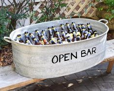 a metal tub filled with beer bottles sitting on top of a wooden bench