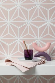 a pink vase sitting on top of a white shelf next to a cup and saucer