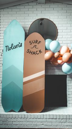 two surfboards are hanging on the wall next to an open fire place with balloons