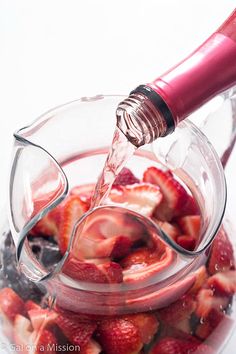 strawberries are being poured into a glass container