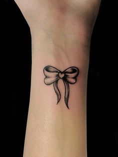 a wrist tattoo with a bow on it