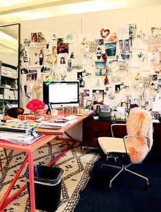 an office with a desk, computer and chair in front of a wall full of pictures