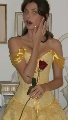 a woman in a yellow dress holding a rose