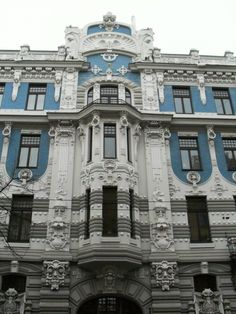 an ornate building with blue and white paint on the front, windows and balconies