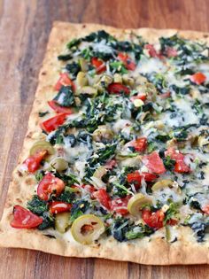 a pizza topped with cheese and vegetables on top of a wooden table