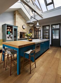 a kitchen with an island and skylight in it's center area, surrounded by wooden flooring