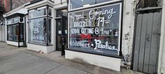 a store front with signs on the windows and doors that say it's opening