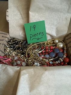 a box filled with lots of different types of bracelets and necklaces on top of paper