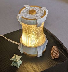 a lamp that is sitting on top of a table next to a small pine cone