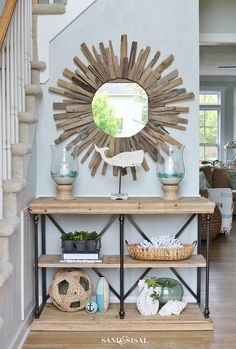 a sunburst mirror on the wall above a shelf with baskets and vases