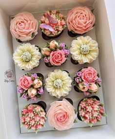 cupcakes decorated with pink and white flowers in a box