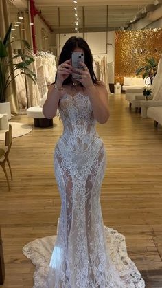 a woman taking a selfie in a wedding dress at a bridal shop with her cell phone