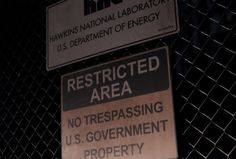 two signs on a fence that say restricted area and no trespassing u s government property