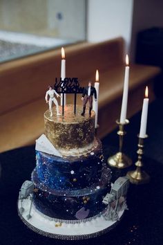 a three tiered cake sitting on top of a table next to two lit candles