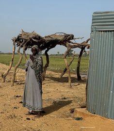 a woman standing in front of a structure made out of branches