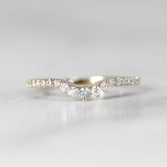 a three stone diamond ring on a white surface with the top half in yellow gold