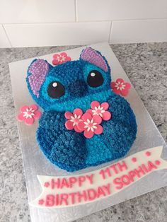 a blue birthday cake with pink flowers and an animal on top that says happy 11th birthday soma