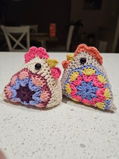 two small crocheted owls sitting on top of a white table next to each other