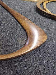 two wooden curved mirrors sitting on the floor next to each other in an area with carpeting