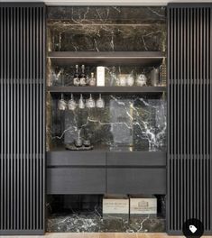 a room with black and white marble walls, wooden flooring and shelves filled with glassware