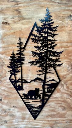 a bear and cub in the woods cut out of metal on wood with pine trees