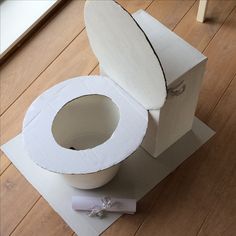 an open toilet paper box sitting on top of a wooden floor next to a roll of toilet paper