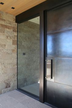 a bathroom with a glass door and stone wall