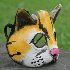 a yellow and black cat mask sitting on top of a wooden table