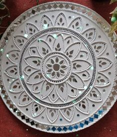 a decorative white plate sitting on top of a red cloth covered floor next to a potted plant