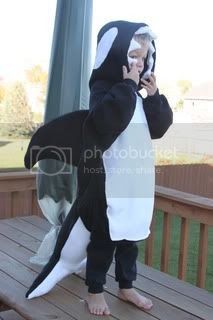 an older man in a penguin costume on the porch with his cell phone to his ear