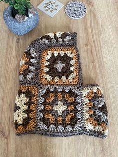 two crocheted potholders sitting on top of a wooden floor next to a plant