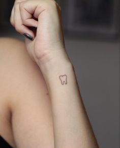 a woman with a small tooth tattoo on her arm