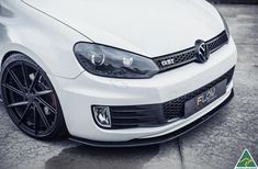 the front end of a white car parked in a parking lot