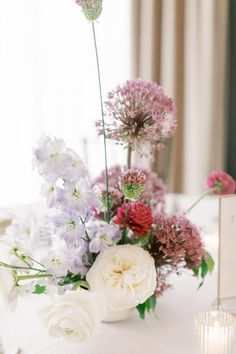 a vase filled with lots of flowers on top of a white table cloth covered table