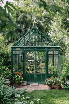 a small green house surrounded by greenery and flowers in the garden with potted plants