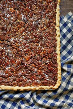 a pecan pie sitting on top of a blue and white checkered cloth