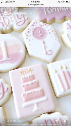 decorated cookies with pink and white icing are arranged on a table in the shape of baby's first birthday